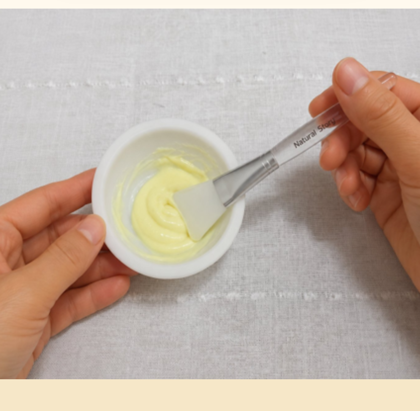 Hands mixing a pale yellow preparation in a bowl with a spatula